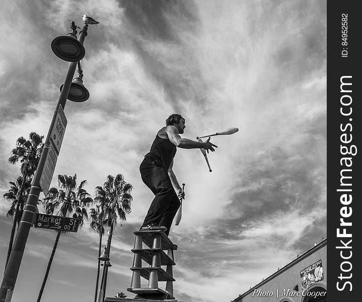 Street Acrobat juggles atop 12 glasses and an aluminum roller. On the boardwalk in Venice Beach California. Street Acrobat juggles atop 12 glasses and an aluminum roller. On the boardwalk in Venice Beach California