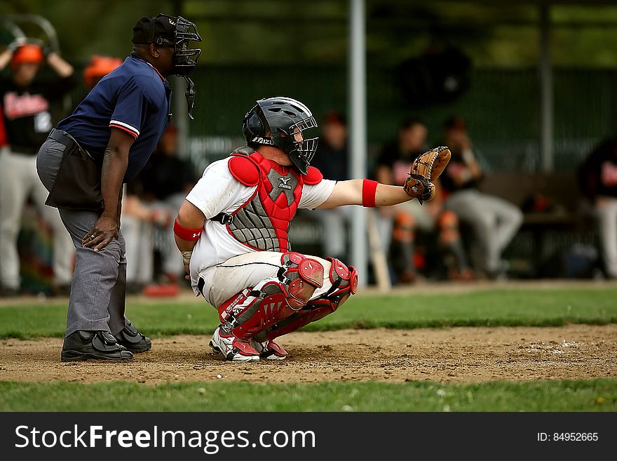 White and Red Baseball Player With Black Face Helmet and Brown Leather Mitts