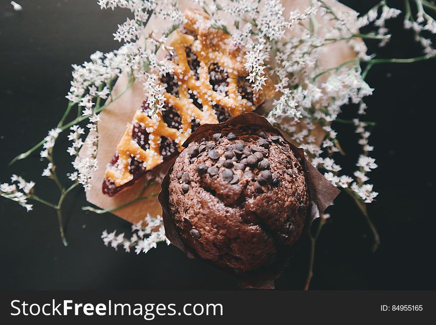 A chocolate cupcake and a slice of pie with wild flowers. A chocolate cupcake and a slice of pie with wild flowers.