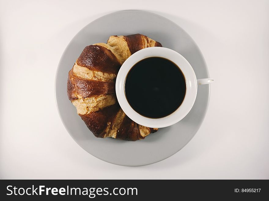 A cup of coffee with a fresh croissant. A cup of coffee with a fresh croissant.