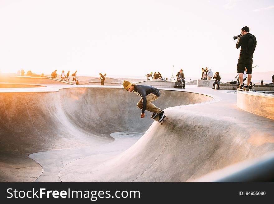 A group of skateboarders in a skate park with a photographer photographing a skater in a bowl. A group of skateboarders in a skate park with a photographer photographing a skater in a bowl.