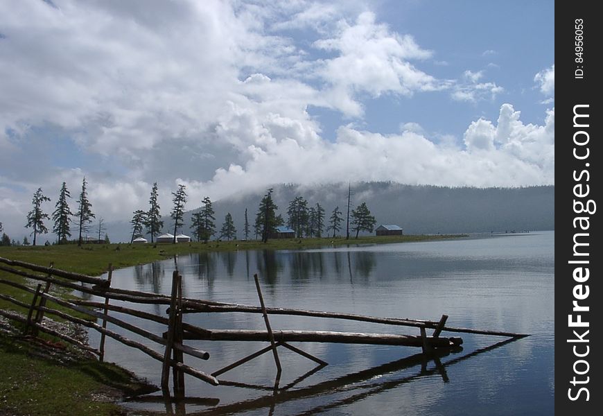 Wooden fence posts along waterfront in mountains against blue skies. Wooden fence posts along waterfront in mountains against blue skies.