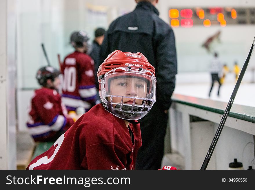 Youth hockey player in safety equipment on bench during game.