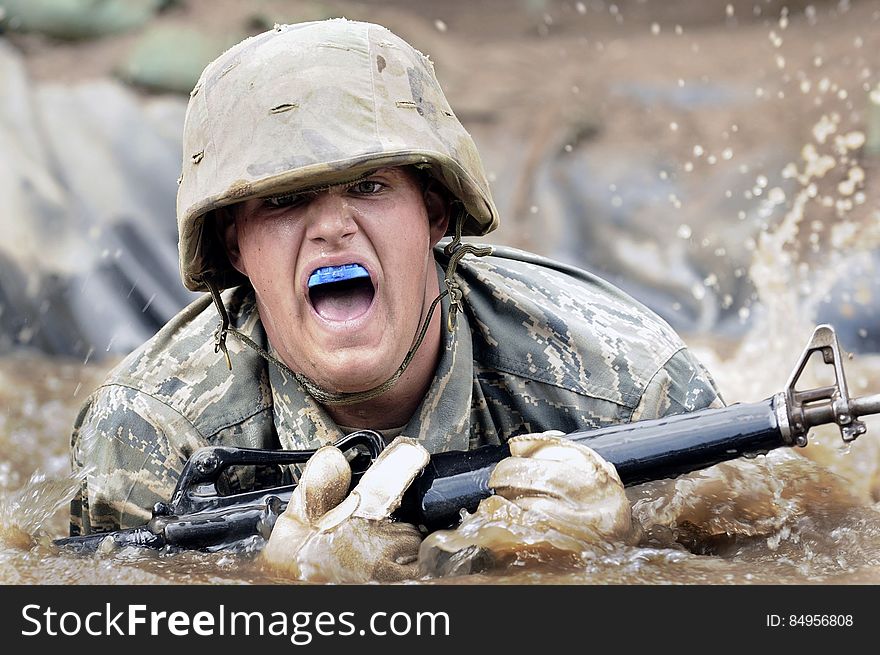 A soldier with a shotgun in muddy water. A soldier with a shotgun in muddy water.