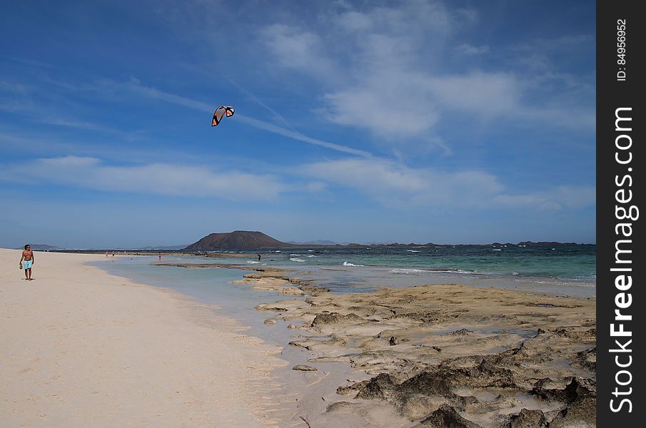 A man flying a kite above a sandy beach. A man flying a kite above a sandy beach.