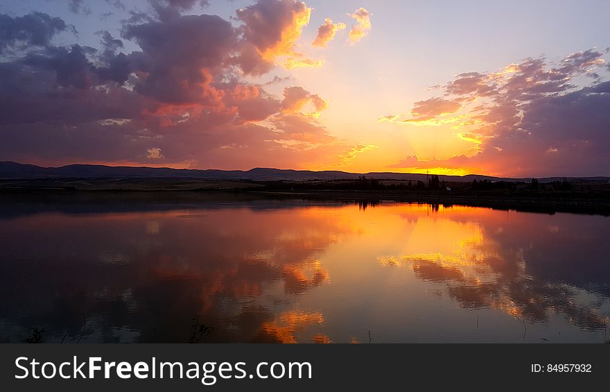 A sunset on a lake with colorful skies reflecting on the still waters. A sunset on a lake with colorful skies reflecting on the still waters.