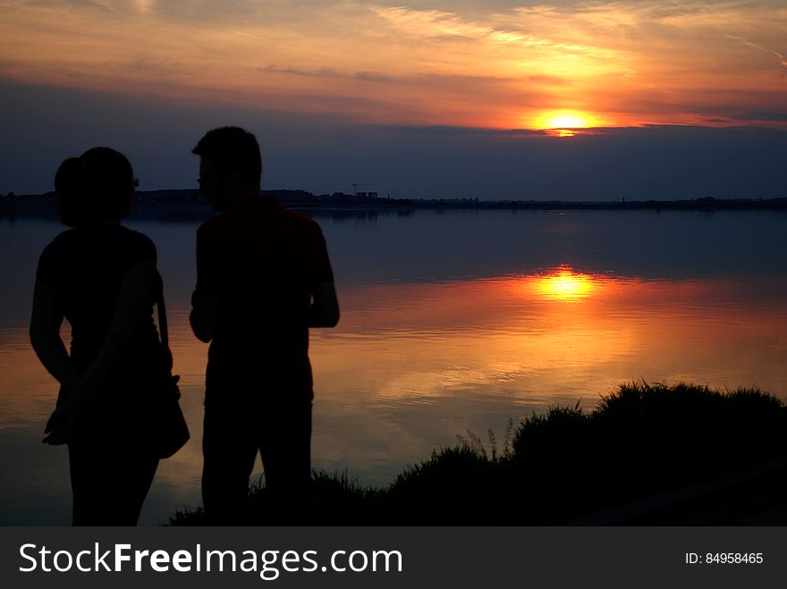 Silhouette of Man and Woman Near Water during Sun Set