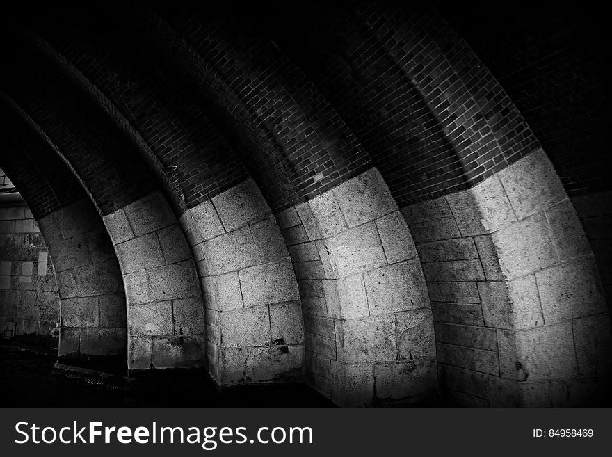 A black and white photo of arches made of stone and brick. A black and white photo of arches made of stone and brick.