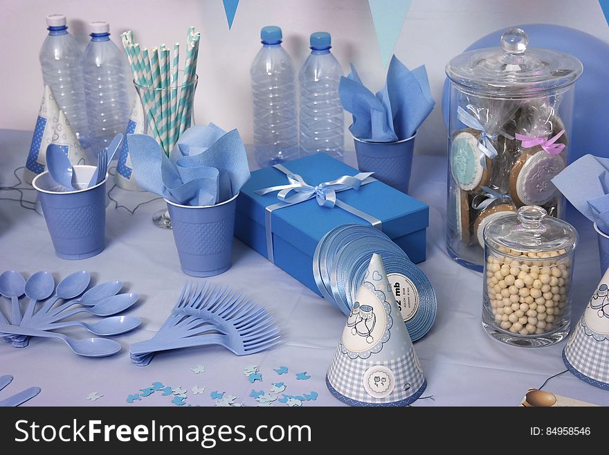 A birthday table setting with blue-colored items, utensils, cups and party items. A birthday table setting with blue-colored items, utensils, cups and party items.