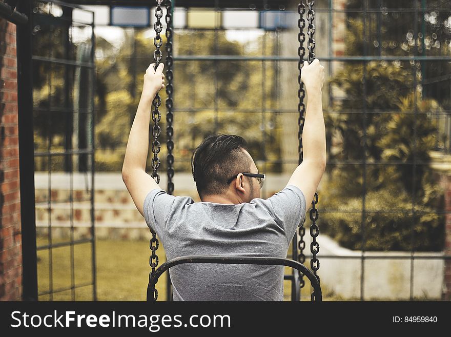 A man sitting in a swing on playground. A man sitting in a swing on playground.