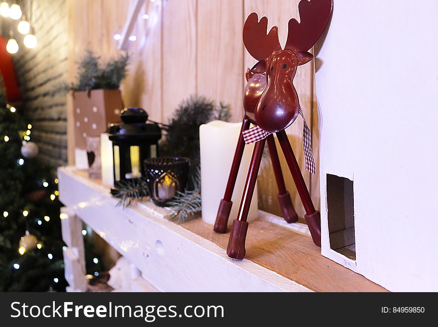A shelf in the room with various Christmas decorations, tree, candles, elk and other items. A shelf in the room with various Christmas decorations, tree, candles, elk and other items.