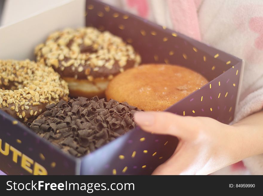 A woman holding a box of fried donuts. A woman holding a box of fried donuts.