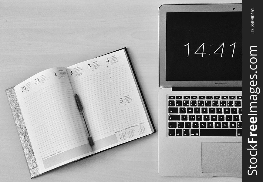 A laptop computer on the desk with an open calendar next to it. A laptop computer on the desk with an open calendar next to it.