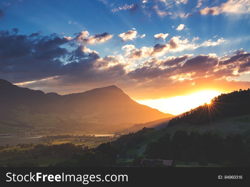 A landscape with sun setting behind mountains. A landscape with sun setting behind mountains.