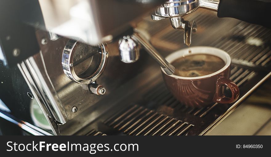 A coffee shop machine with a cup of espresso being prepared. A coffee shop machine with a cup of espresso being prepared.