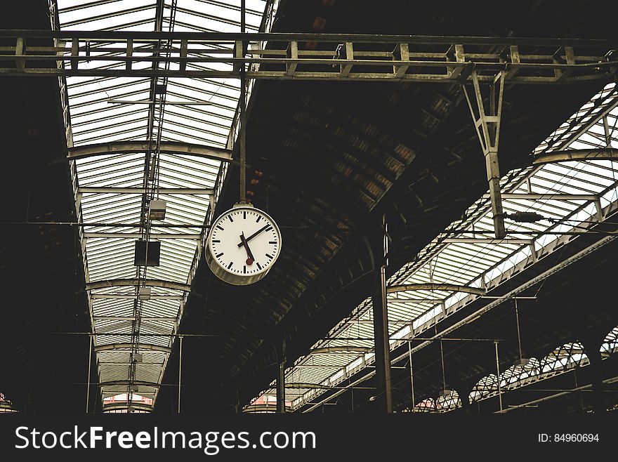Roof over a railway station with glass windows for lighting and a large clock for passenger information. Roof over a railway station with glass windows for lighting and a large clock for passenger information.