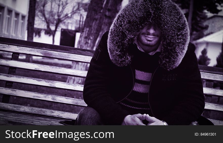 Man with fur collar on bench
