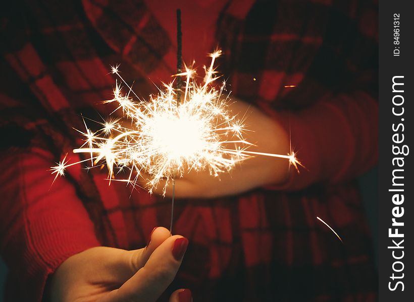 A woman holding a burning sparkler . A woman holding a burning sparkler .