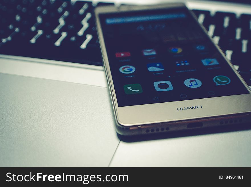 A mobile phone on top of the laptop keyboard. A mobile phone on top of the laptop keyboard.