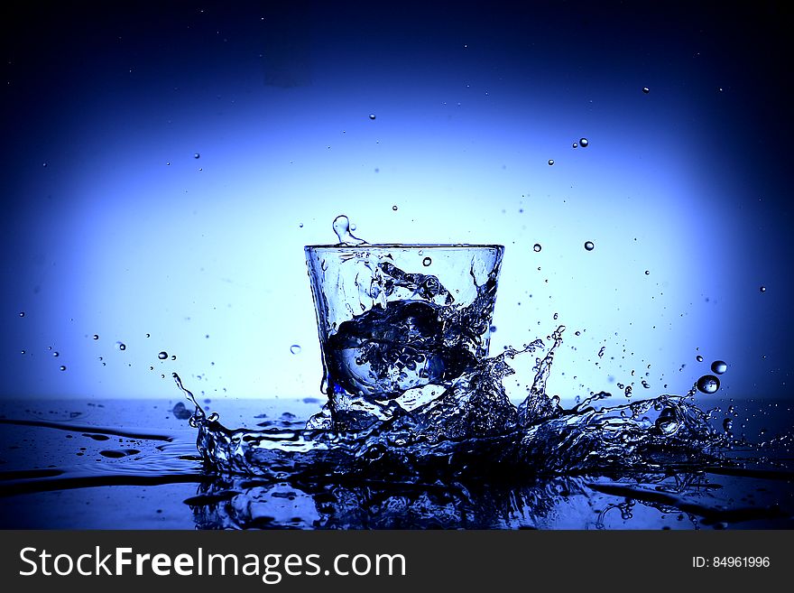 Water splash around a glass on a blue background. Water splash around a glass on a blue background.
