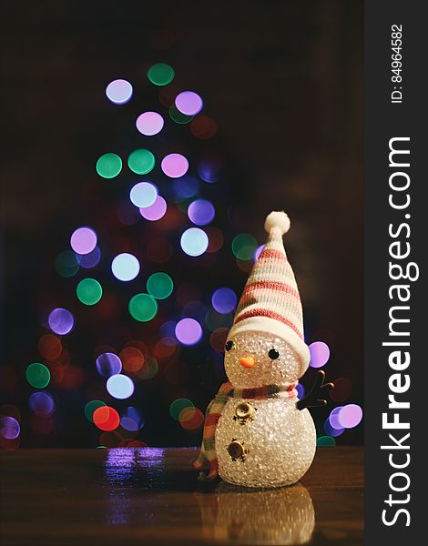 A toy snow man in front of light in the shape of a Christmas tree. A toy snow man in front of light in the shape of a Christmas tree.