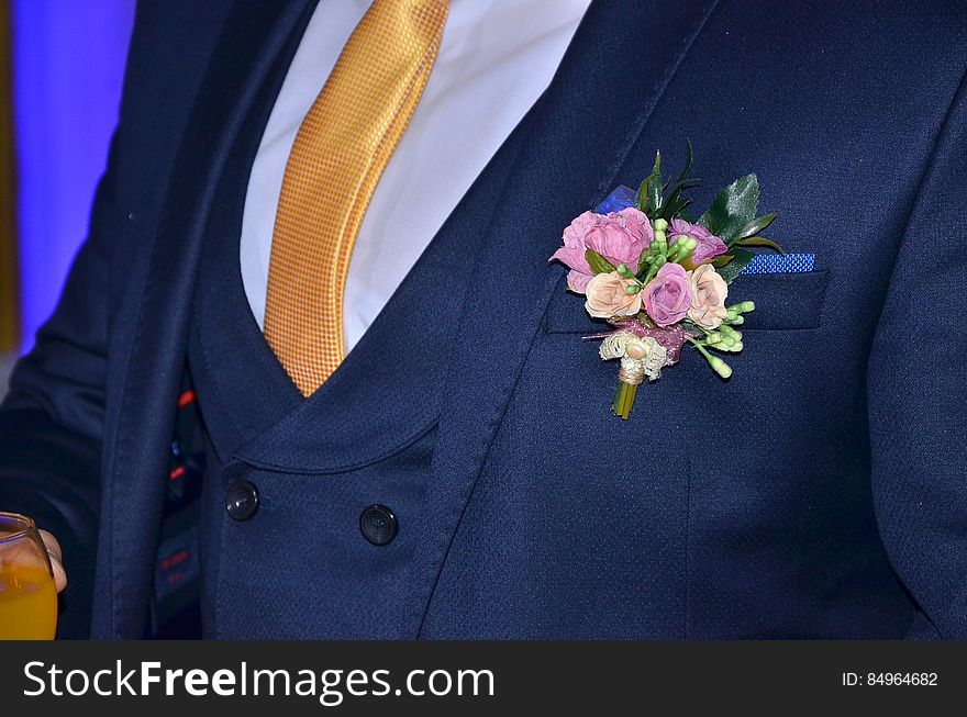 A close up of a wedding lapel pin on groom's dark blue tuxedo.