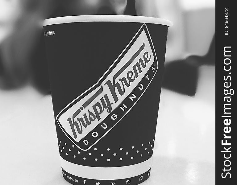 Black and white side view of Krispy Kreme Doughnuts cup of coffee.