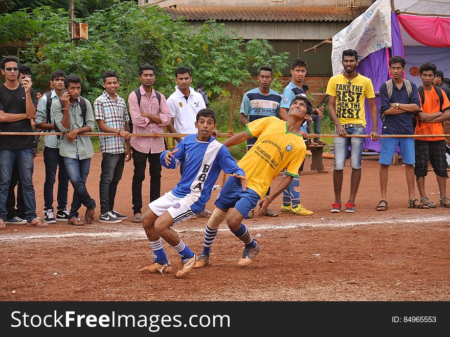 Youth soccer players in dirt field with spectators. Youth soccer players in dirt field with spectators.