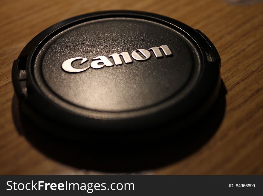 A close up of a camera lens cap on table.