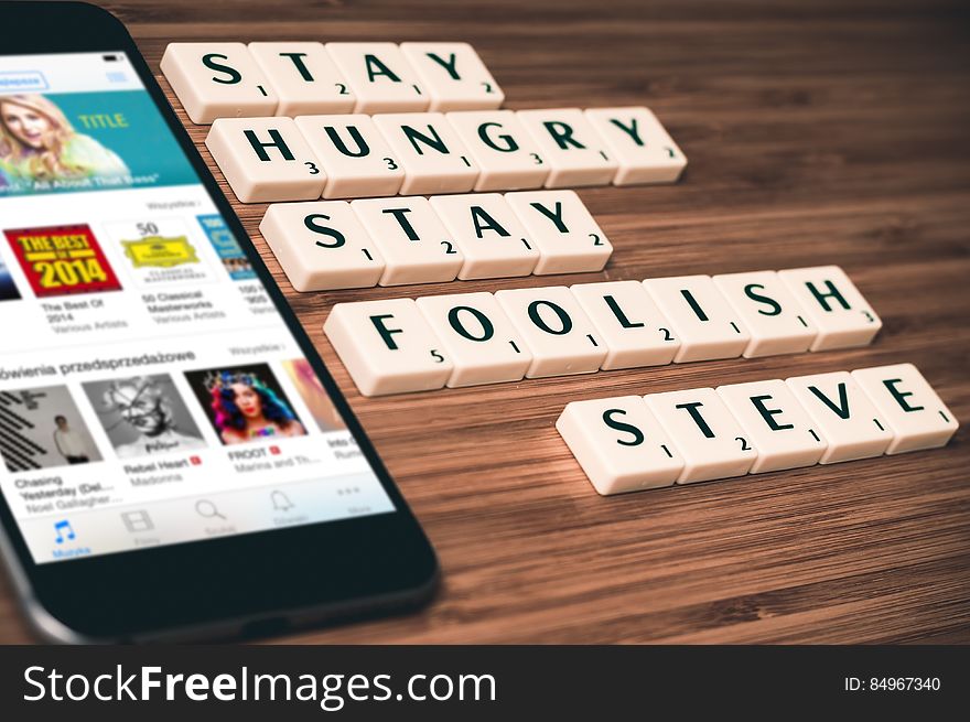 A smartphone with letter blocks forming the quote "Stay hungry stay foolish" accredited to Steve Jobs.