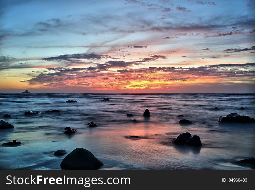 Silhouette of Stones on Seawater during Sunset