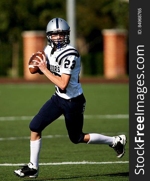 An American football player running on the field with the ball.