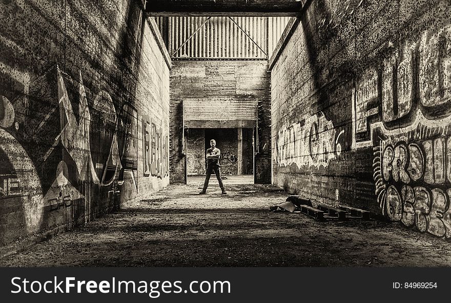A man standing in urban ruins with graffiti on the walls. A man standing in urban ruins with graffiti on the walls.