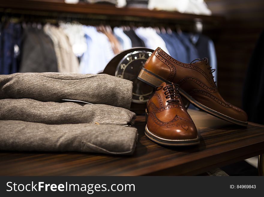 Men`s brown leather shoes and trousers on a shelf in a store. Men`s brown leather shoes and trousers on a shelf in a store.