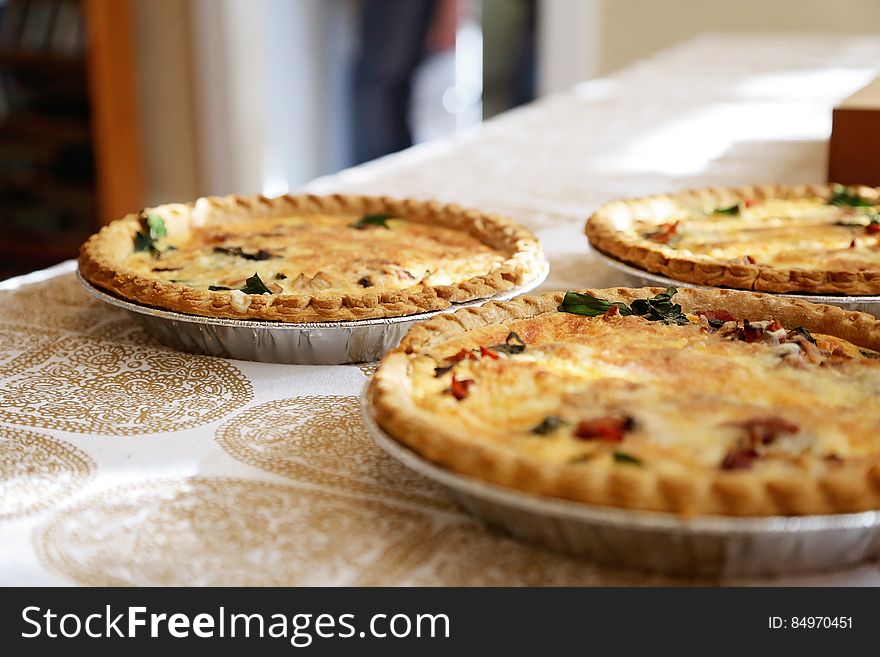 Three freshly baked quiche pies on a table.