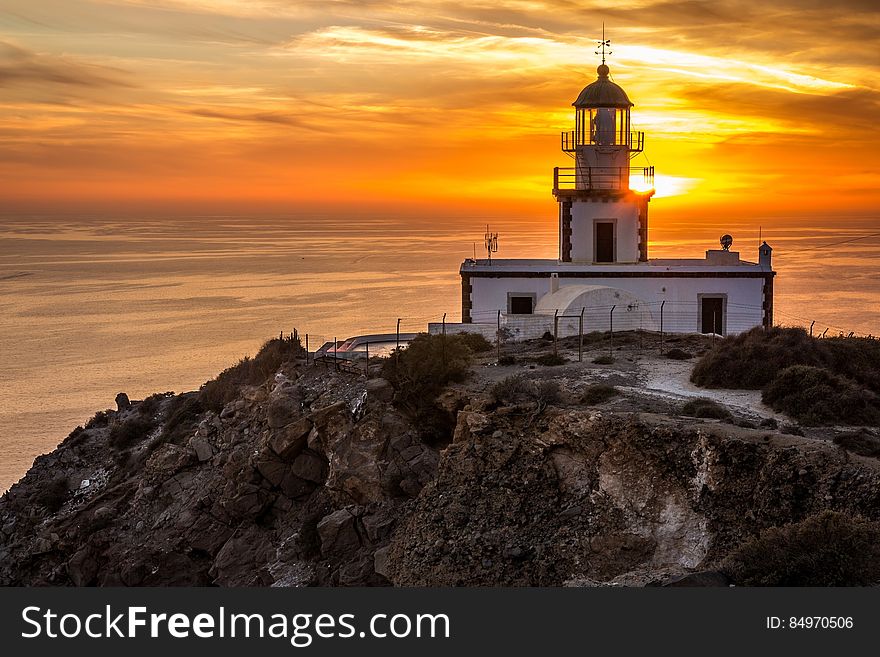 The Akrotiri Lighthouse in Santorini, Greece, at sunset.