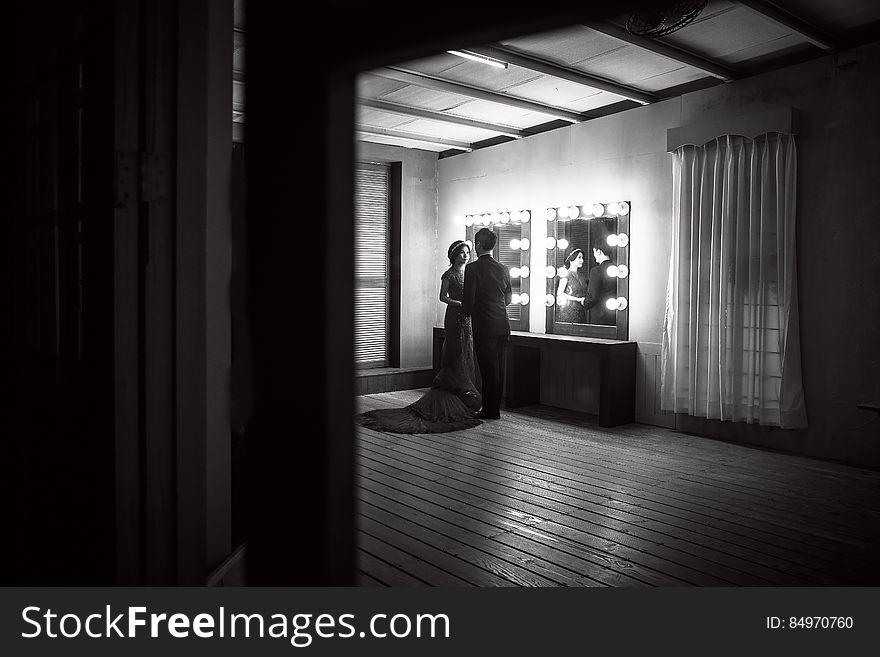 Monochrome view of romantic couple by mirrors in theater dressing room. Monochrome view of romantic couple by mirrors in theater dressing room.
