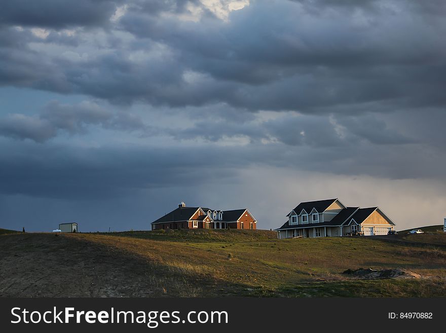 A view of farmland and farm houses under cloudy skies. A view of farmland and farm houses under cloudy skies.