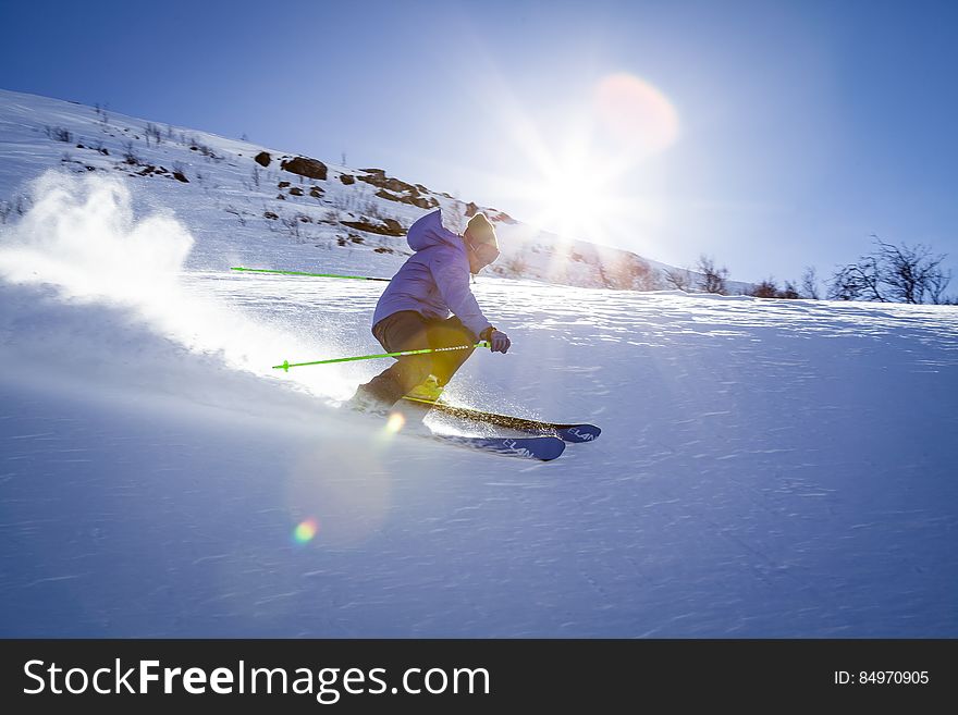 A skier speeding down a hill in the winter. A skier speeding down a hill in the winter.