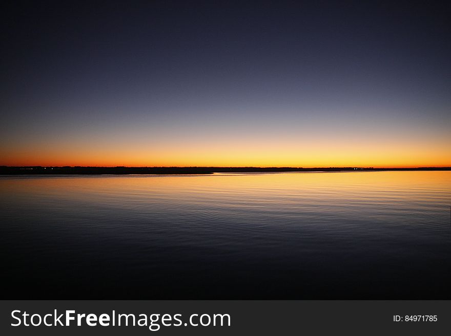Silhouette of Calm Sea Under Blue and Orange Clear Sky during Sunset