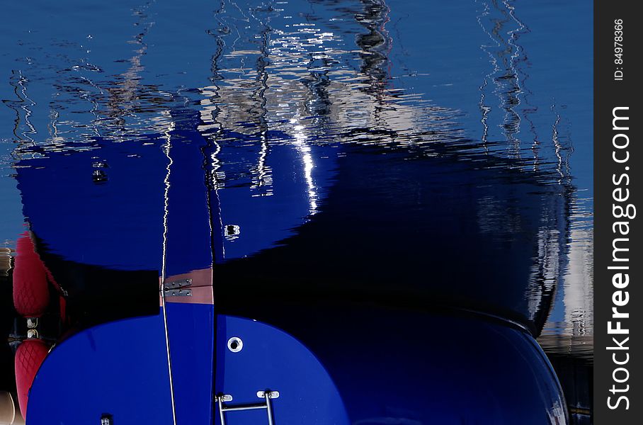 Bow of blue ship reflecting in waters.
