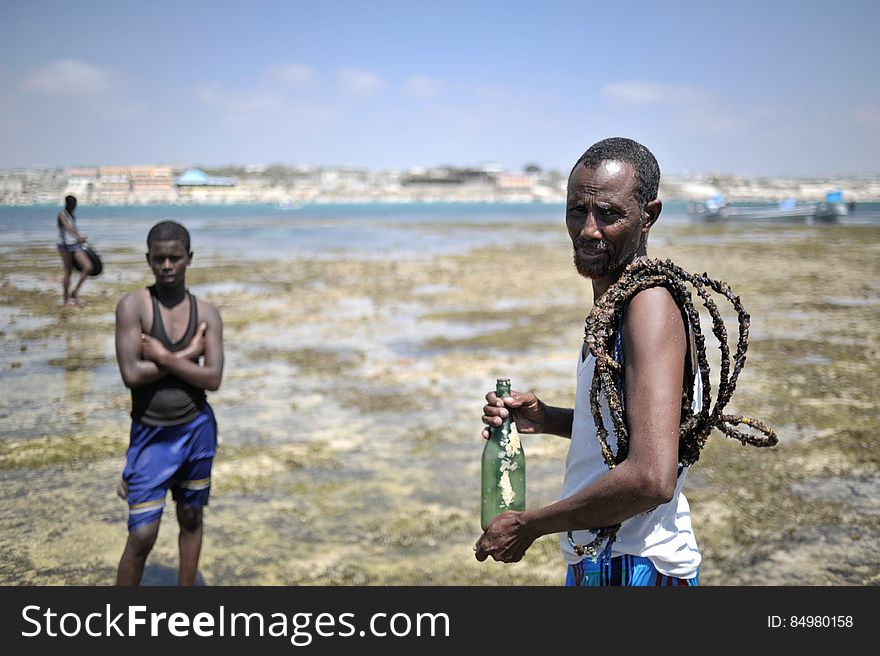 A Somali man carries a bottle and rope he found on a sand bank off of Lido beach in Mogadishu, Somalia, on January 31. The Mogadishu lifeguards, consisting entirely of a volunteer force of fisherman, began patrolling Lido beach in September 2013 after a spate of drownings. Mogadishu&#x27;s beaches have become a popular destination for the city&#x27;s residents since al Shabab withdrew the majority of its militants from the city in 2011. AU UN IST PHOTO / Tobin Jones. A Somali man carries a bottle and rope he found on a sand bank off of Lido beach in Mogadishu, Somalia, on January 31. The Mogadishu lifeguards, consisting entirely of a volunteer force of fisherman, began patrolling Lido beach in September 2013 after a spate of drownings. Mogadishu&#x27;s beaches have become a popular destination for the city&#x27;s residents since al Shabab withdrew the majority of its militants from the city in 2011. AU UN IST PHOTO / Tobin Jones
