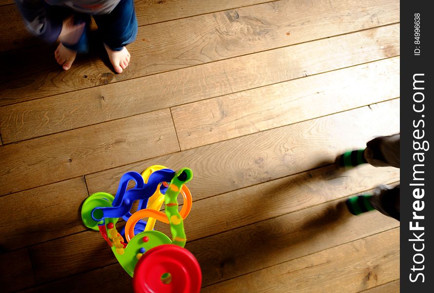 A colorful toy and children's feet on the floor. A colorful toy and children's feet on the floor.