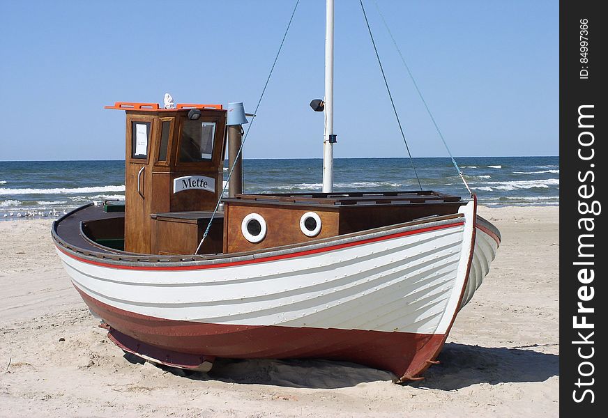 White and Brown Speedboat on White Sand Beside Ocean during Daytime