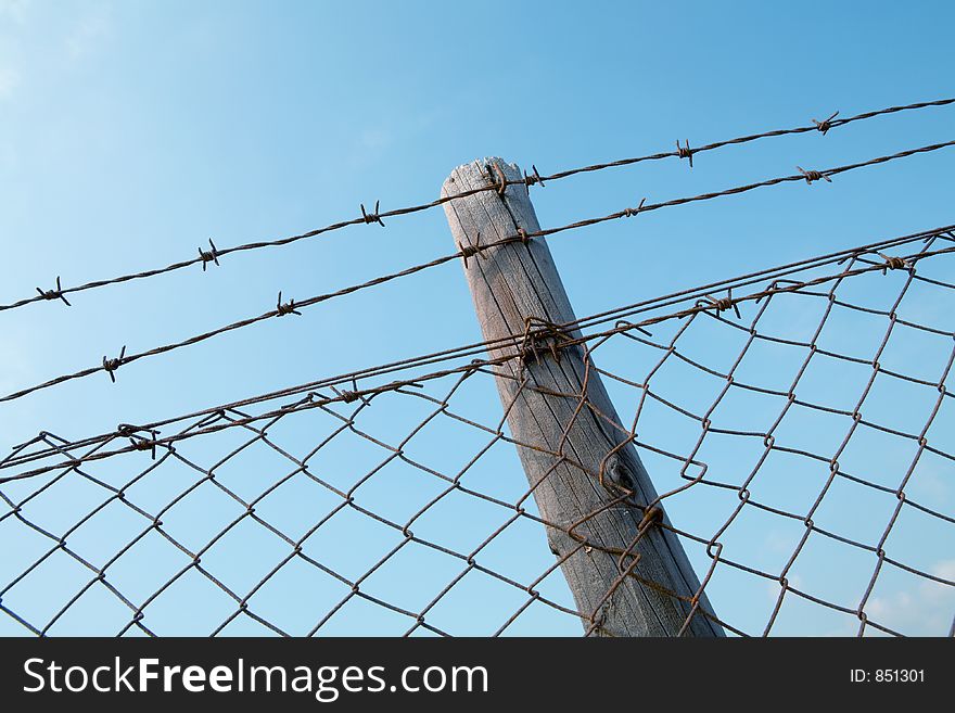 Barbed wire fence against blue sky