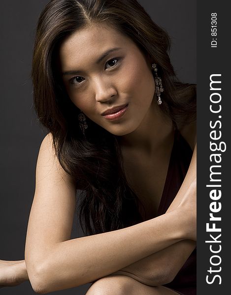 A pretty young asian model sitting with arms across her chest. A pretty young asian model sitting with arms across her chest