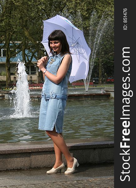 Pretty young woman with umbrella standing near fountain. Pretty young woman with umbrella standing near fountain