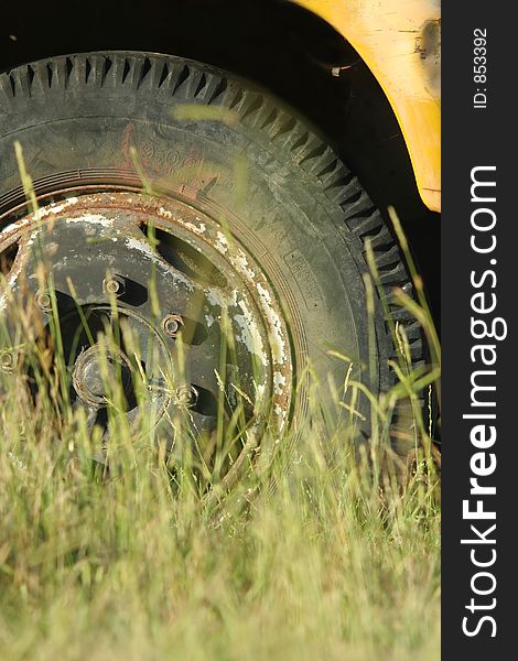 Abandoned truck image; telephoto shot of tyre (or tire) shot through grass. Abandoned truck image; telephoto shot of tyre (or tire) shot through grass.