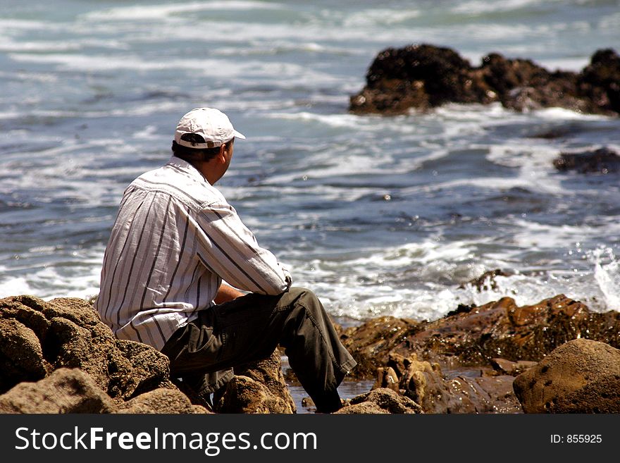 Man sitting on rocks in the ocean. Man sitting on rocks in the ocean