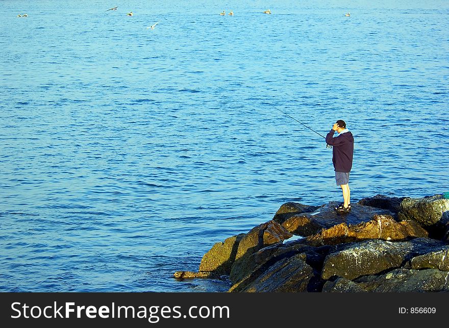 Man fishing on the rocks at beach